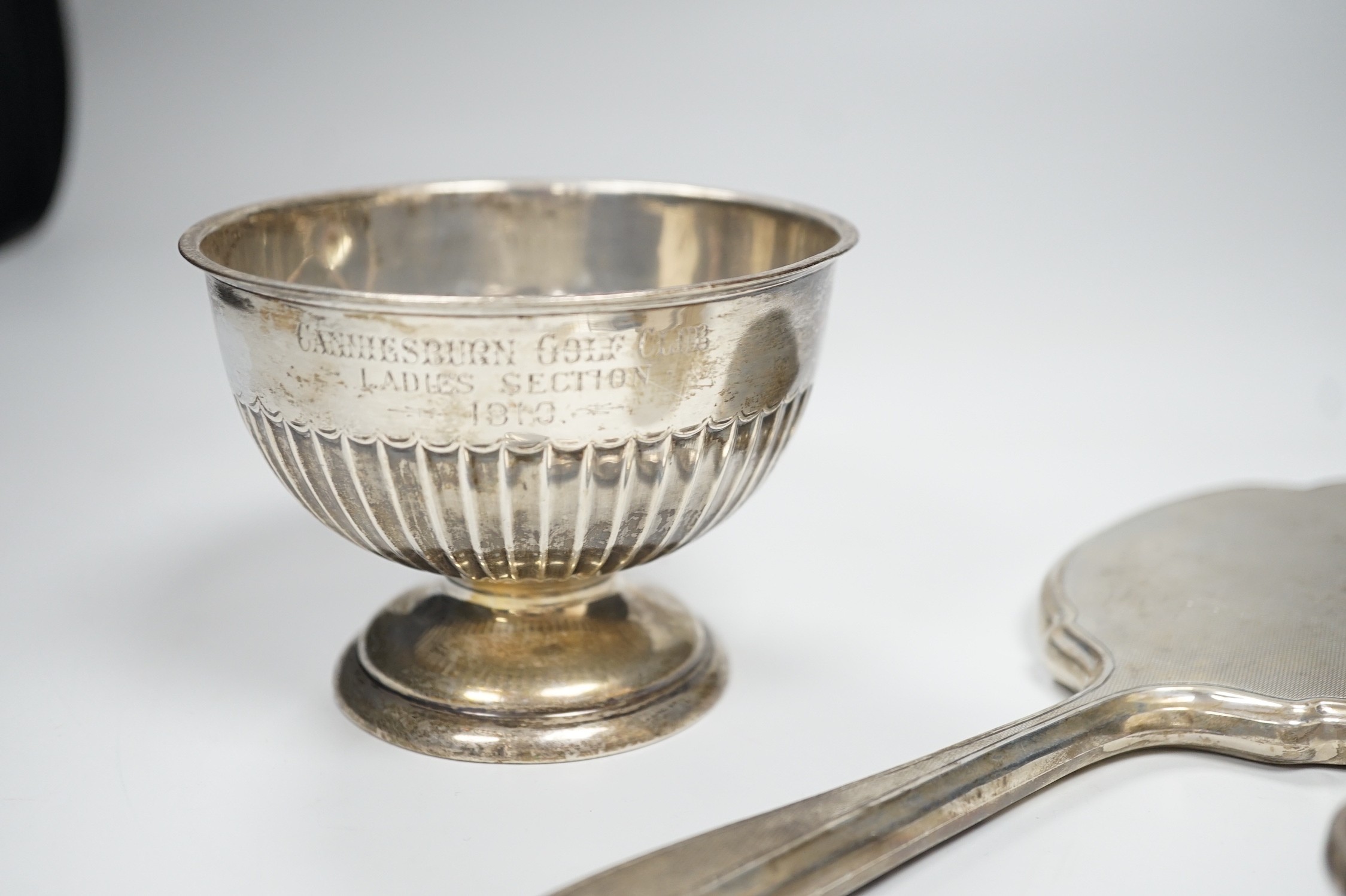 An Edwardian demi-fluted silver small presentation pedestal bowl, Sheffield, 1904, diameter 10.9cm and a silver mounted hand mirror and clothes brush.